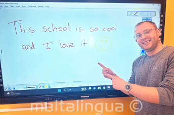 Un estudiante tras escribir una opinión positiva de la escuela en la pizarra