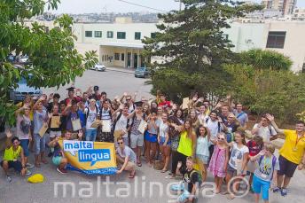 Un grupo grande de jóvenes estudiantes haciendo la ola fuera de la escuela