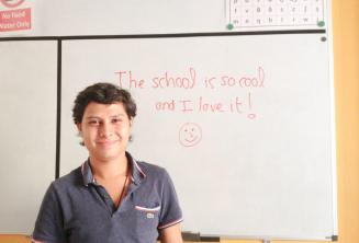 Un estudiante tras escribir una opinión positiva de la escuela en la pizarra